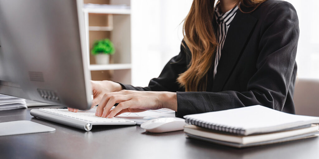 eine weibliche Person schreibt auf einer PC-Tastatur